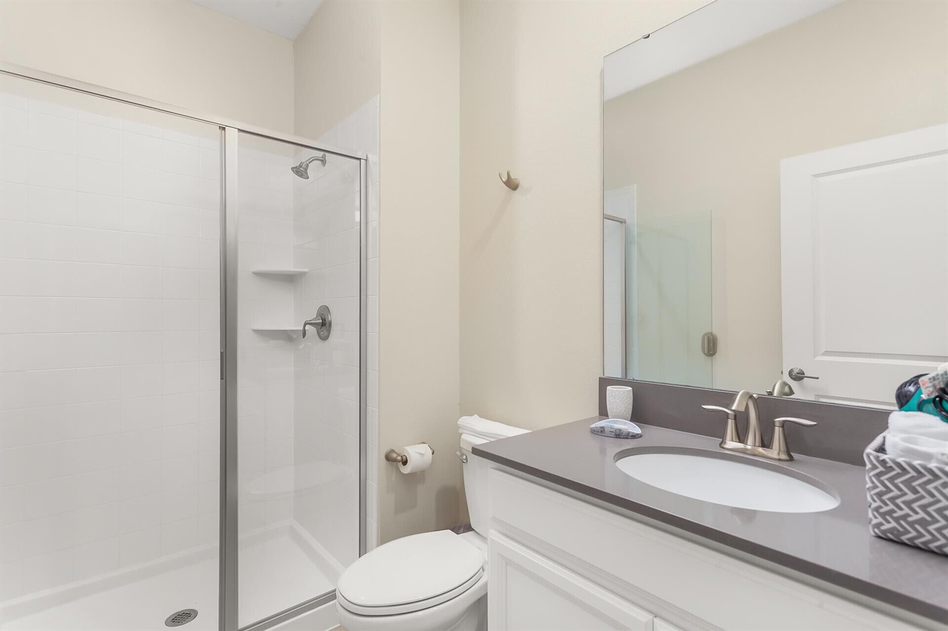 Une salle de bain avec une douche à parois de verre, des toilettes blanches, un lavabo avec un miroir et un porte-serviettes.