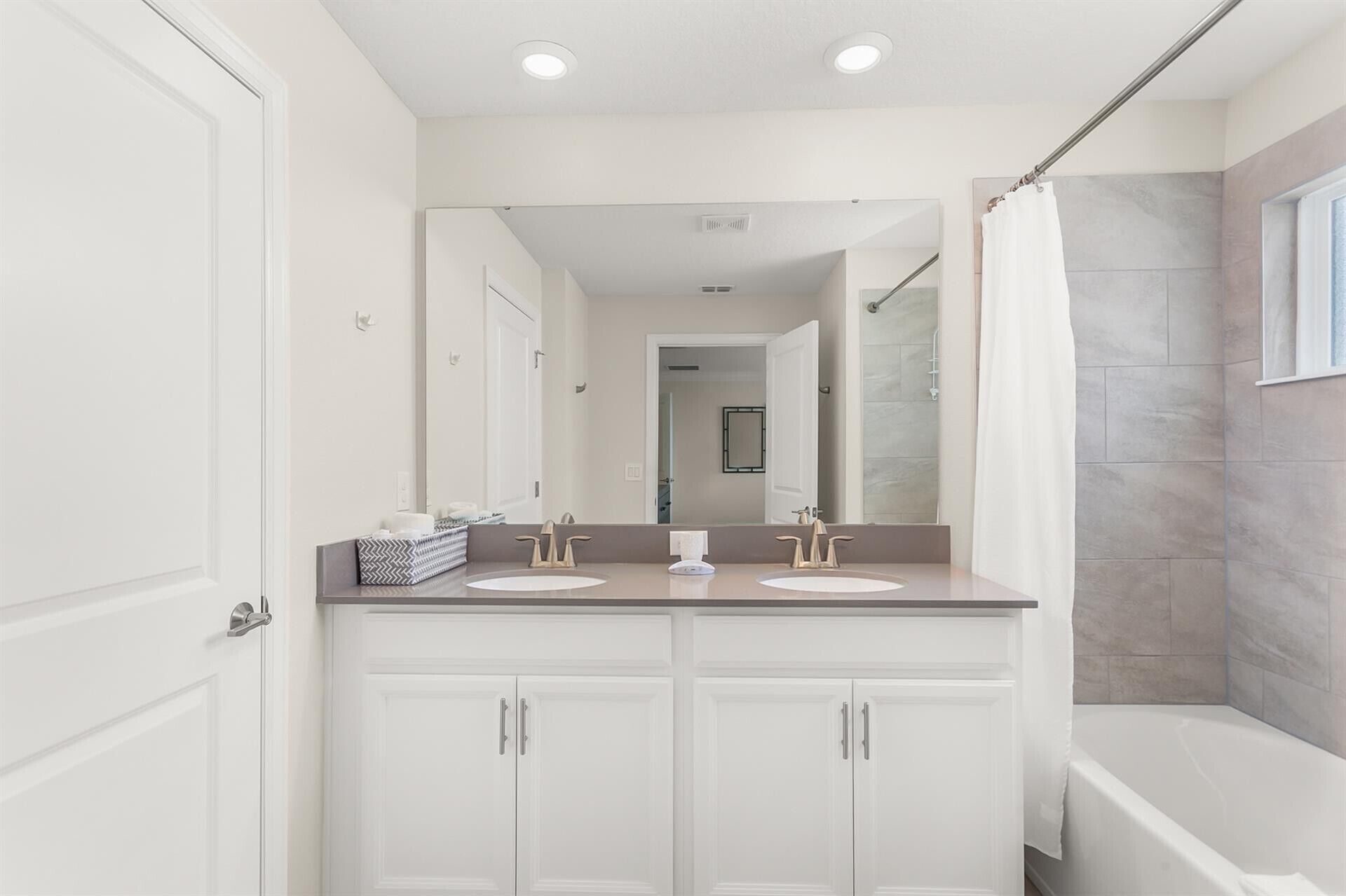 A bathroom with a double vanity, a large mirror, and a shower area.