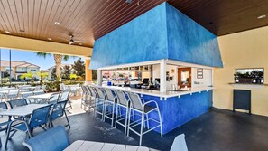 Un área de bar al aire libre con mostrador azul, asientos y vistas de los edificios circundantes.