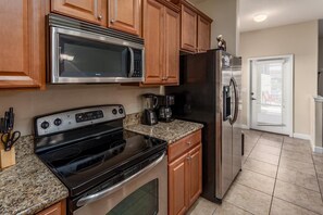 A kitchen with a stove, microwave, refrigerator, and coffee maker. - Last Minute Disney Getaway! Townhouse with Private Pool. Book Now! #107663 (Orlando)