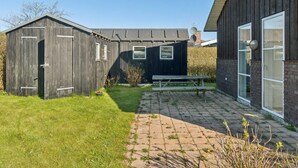 A building with a wooden exterior, a brick patio, and a bench. - 5 Star Holiday Home in Svendborg (Svendborg)