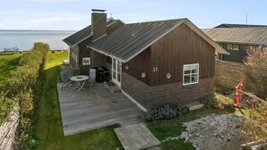 A wooden house with a deck and a view of the sea. - 5 Star Holiday Home in Svendborg (Svendborg)