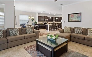A living room with two sofas, a coffee table, and a kitchen in the background. - Last Minute Disney Getaway! Luxury Villa with Private Pool. Book Now! #107669 (Orlando)