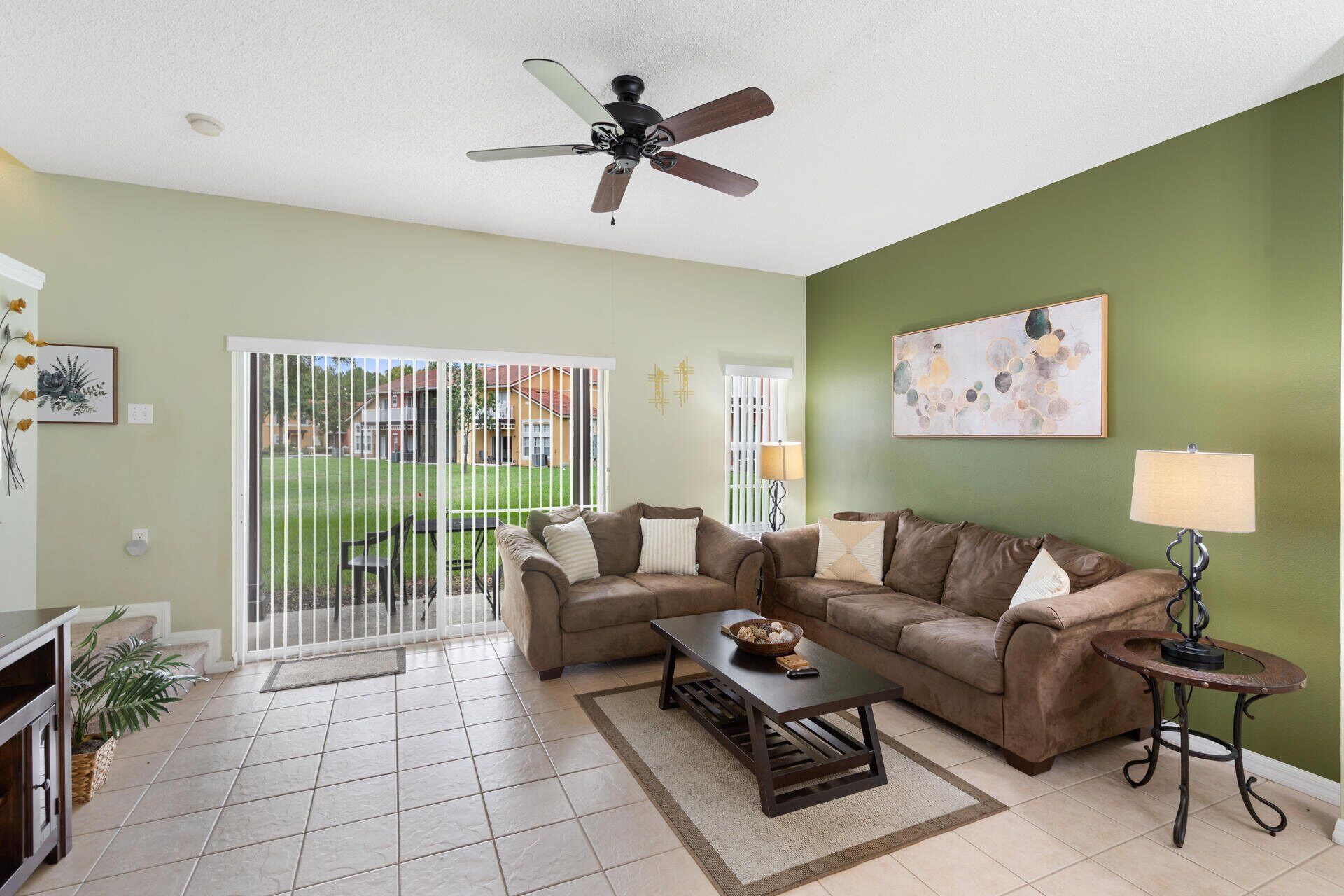 A living room with a sofa set, a coffee table, a lamp, and a ceiling fan.