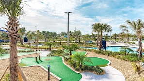 En golfbana med en pool, palmer och en klar himmel.