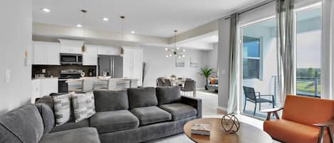 A modern living room with a grey sectional sofa, a round coffee table, and an orange armchair.