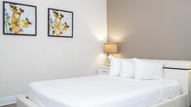 Una camera d'albergo con un letto, due opere d'arte appese alla parete, una lampada da comodino e un comodino.