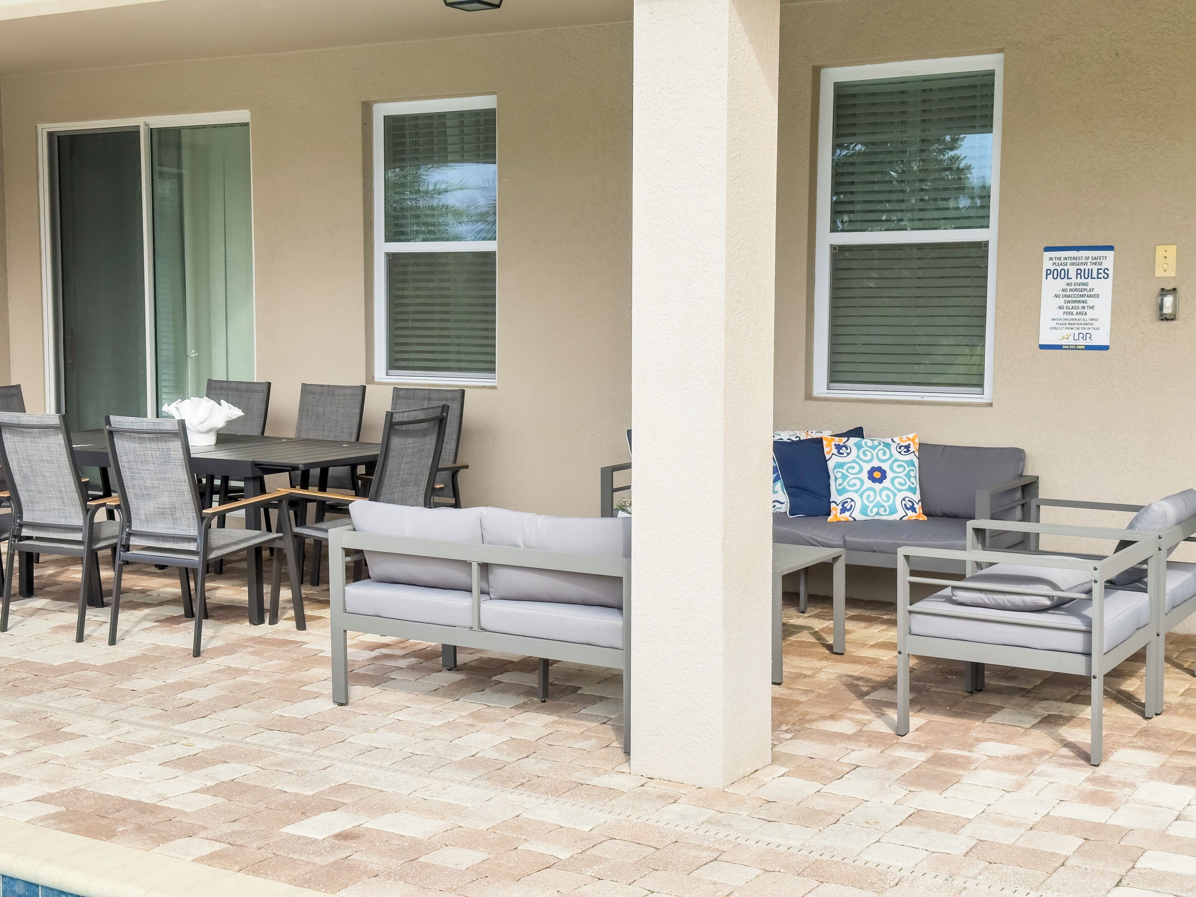 An outdoor seating area with a pool table, chairs, and a sofa.