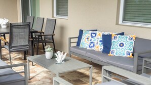 Un'area patio con un divano, sedie, un tavolo e una pianta in vaso.