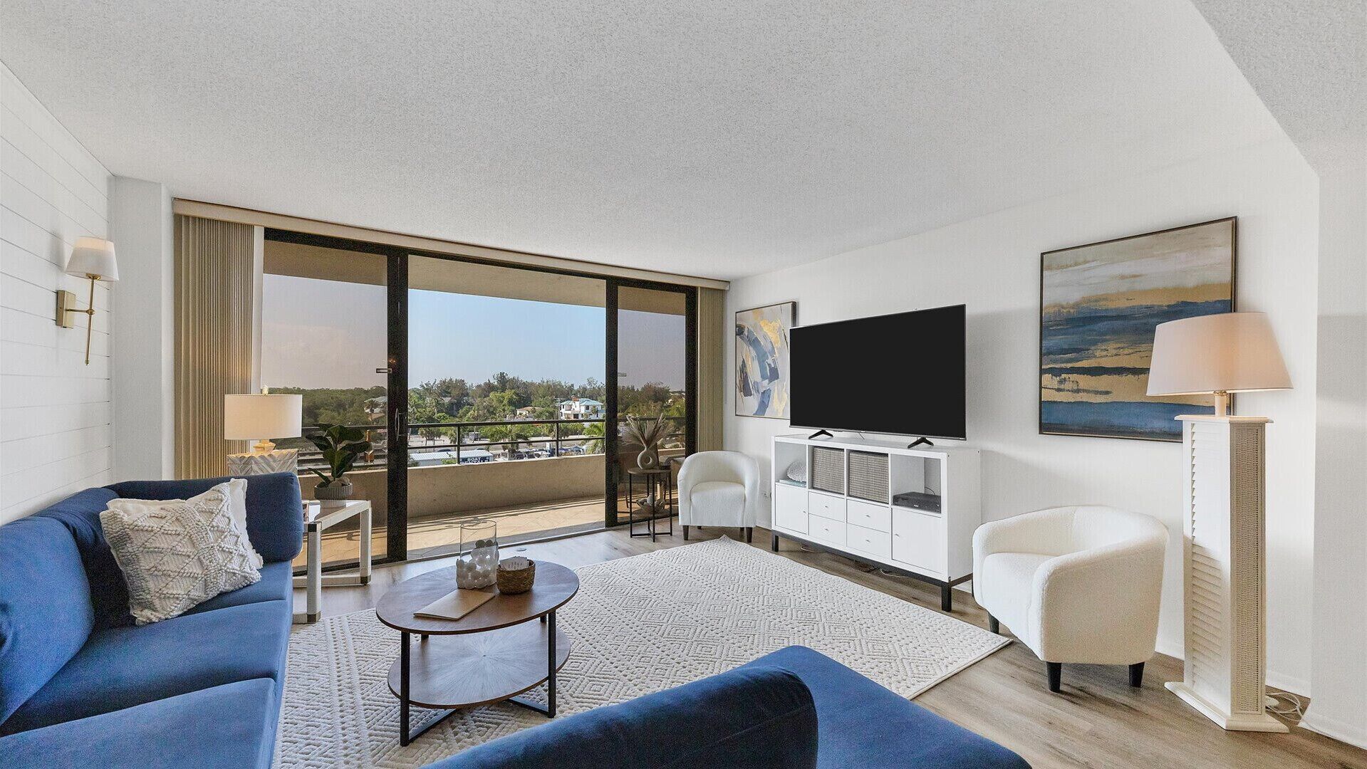 A modern living room with a sofa, armchair, coffee table, and a flat-screen TV.