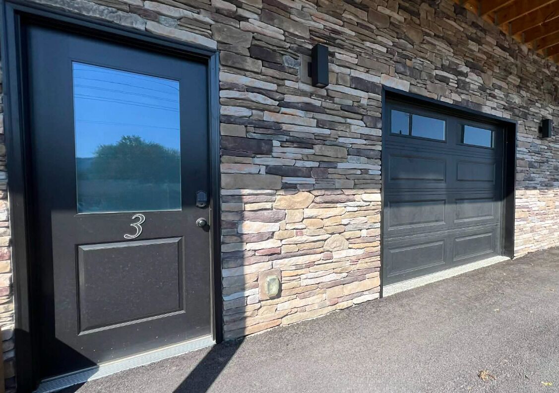 A building with a stone facade and two garage doors.