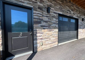 A building with a stone facade and two garage doors. - 🏔️ "Morning Glory: Mountain Views + 4 Baths, Steps to The Island & Dollywood" (Pigeon Forge)