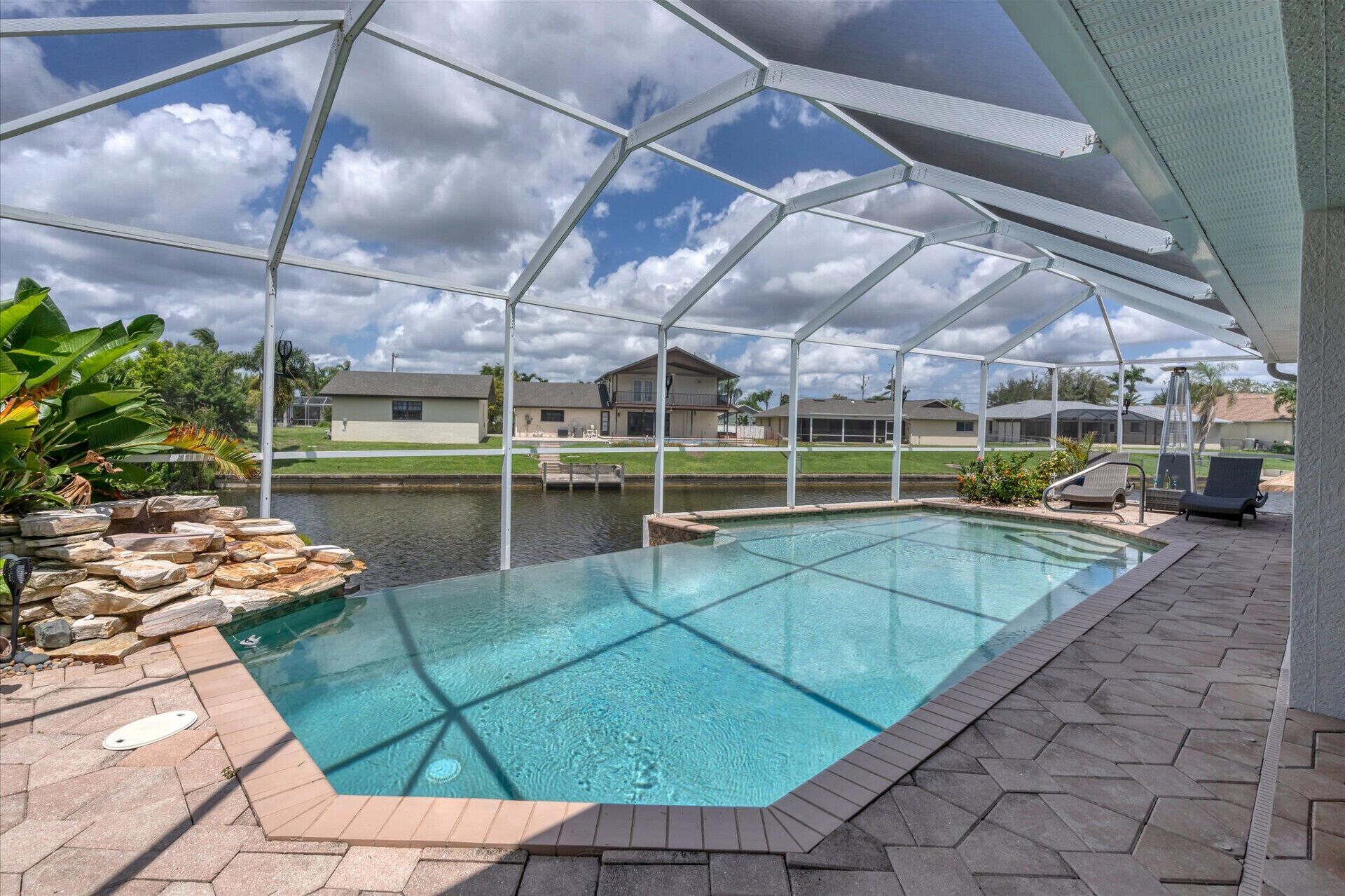 A covered outdoor swimming pool with a view of houses in the background.