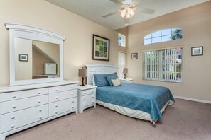 Ein Schlafzimmer mit Bett, Kommode, Nachttischen und Deckenventilator.