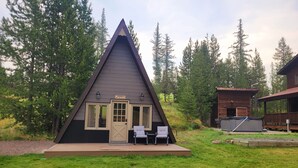Un chalet de forme triangulaire doté d’une terrasse, de deux chaises et d’un petit espace piscine.