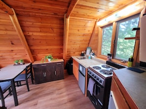 Una cocina compacta con paredes de madera, una mesa de comedor y un ventanal.