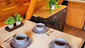 Une table à manger dressée avec des assiettes, des bols et des couverts, et une plante en pot posée sur le comptoir.
