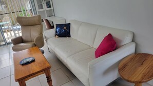 A living room with a sofa, armchair, and a small wooden table. - Villa 1 - Glass House Mountains Retreat (Beerwah)