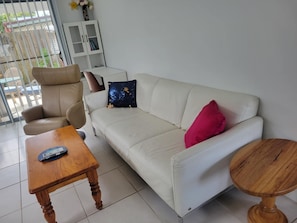 A living room with a sofa, armchair, and a small wooden table. - Villa 1 - Glass House Mountains Retreat (Beerwah)