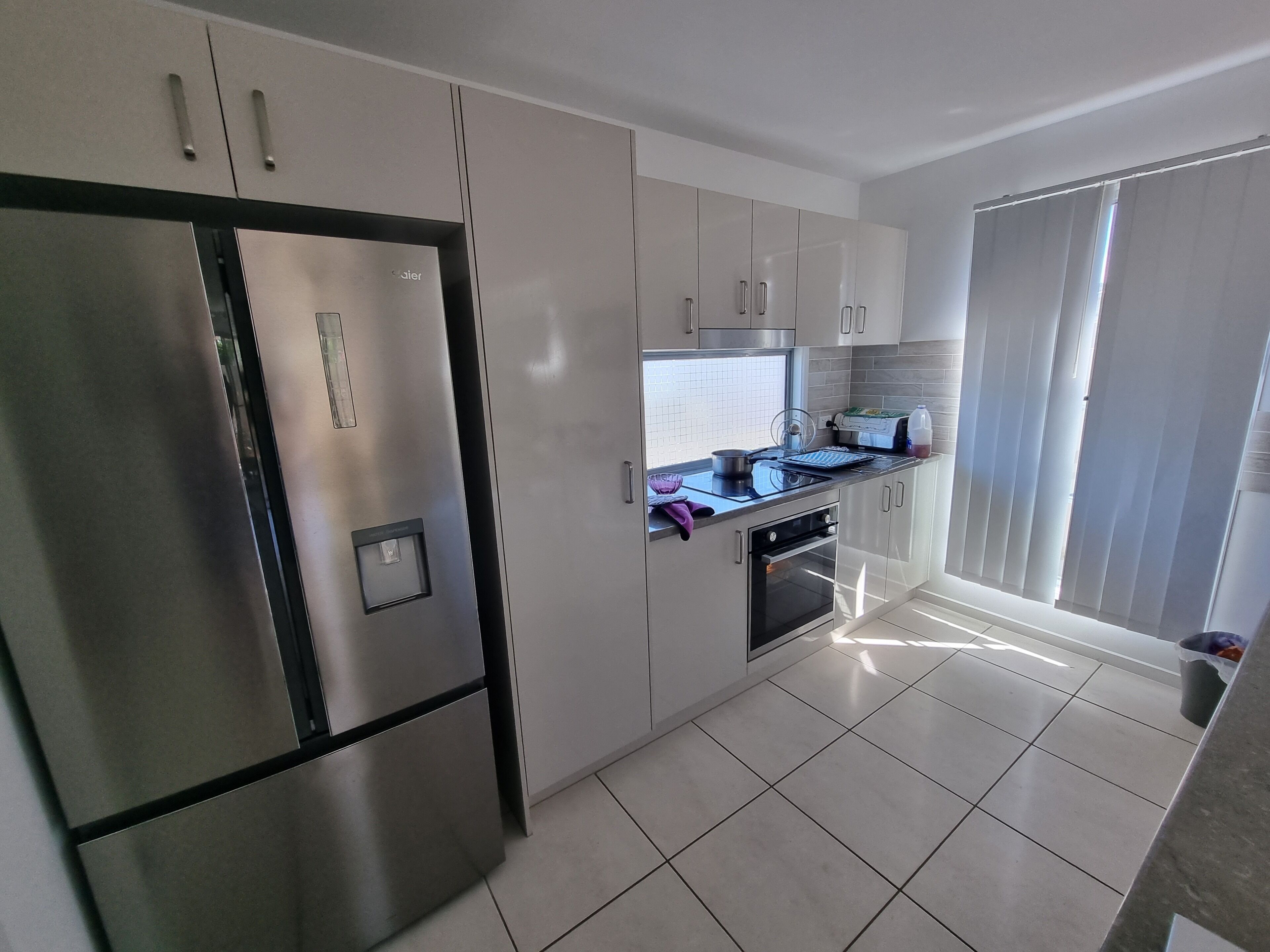 A modern kitchen with stainless steel appliances, white cabinetry, and a tiled floor.