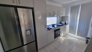 A modern kitchen with stainless steel appliances, white cabinetry, and a tiled floor. - Villa 1 - Glass House Mountains Retreat (Beerwah)
