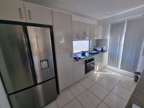 A modern kitchen with stainless steel appliances, white cabinetry, and a tiled floor. - Villa 1 - Glass House Mountains Retreat (Beerwah)