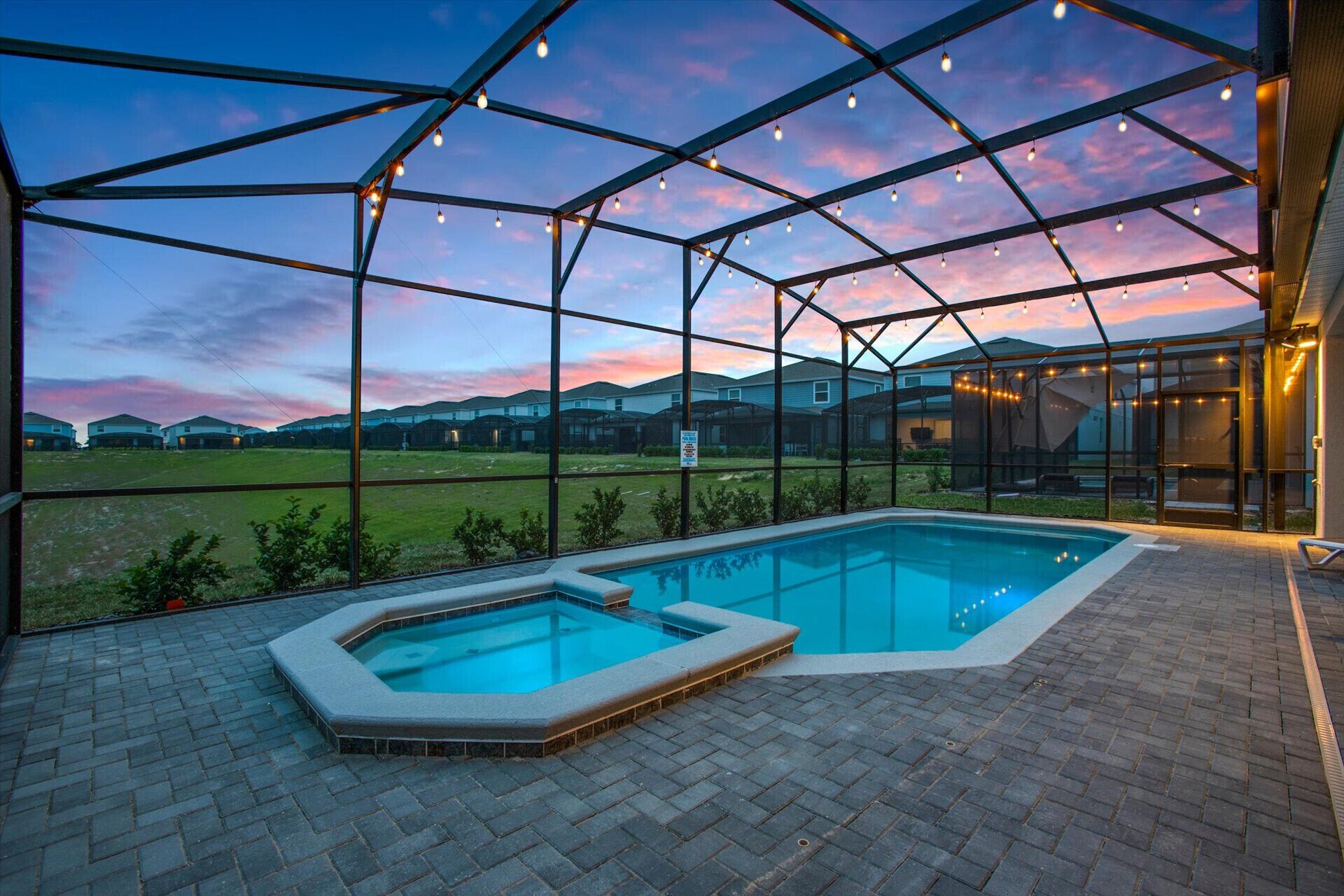 A swimming pool with a glass enclosure, surrounded by a brick patio.