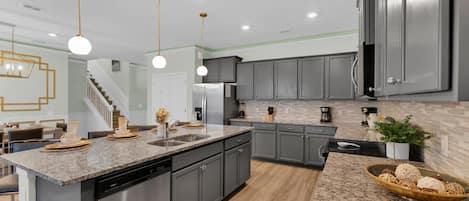 Una cocina moderna con una isla central, electrodomésticos de acero inoxidable e iluminación colgante.