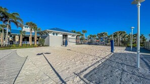 Ein Strandhotel mit Poolbereich, Palmen und blauem Himmel.