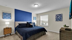 Ein Schlafzimmer mit einem großen Bett, einem Nachttisch, einer Kommode und Bildern an den Wänden.