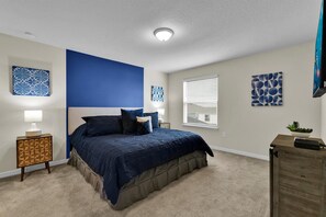 A bedroom with a large bed, a nightstand, a dresser, and artwork on the walls. - Last Minute Disney Getaway! Luxury Villa with Private Pool. Book Now! #112733 (Orlando)