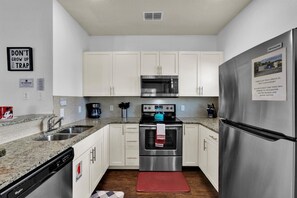 A compact kitchen with white cabinets, a stainless steel refrigerator, a microwave, an oven, and a coffee maker. - Last Minute Disney Getaway! Townhouse with Private Pool. Book Now! #112735 (Orlando)