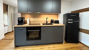 A compact kitchen with grey cabinets, a black refrigerator, a coffee maker, and a Siemens oven. - NEW! FRITZ-ALPCHALETS House Lechtal Apartment  "Stallkarspitze" right on the Lechweg (Vorderhornbach)