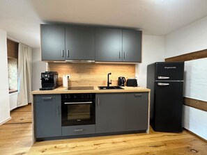 A compact kitchen with grey cabinets, a black refrigerator, a coffee maker, and a Siemens oven.