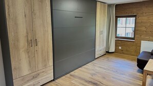 A room with a sliding wardrobe, a window with curtains, and a radiator. - NEW! FRITZ-ALPCHALETS House Lechtal Apartment  "Stallkarspitze" right on the Lechweg (Vorderhornbach)