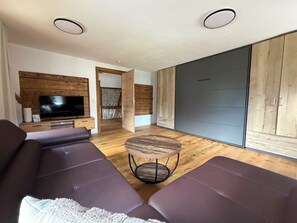 A modern living room with a sectional sofa, a TV, and a wooden cabinet.