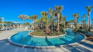 Une piscine à bordures courbes, entourée de palmiers et bordée d’une allée pavée.