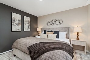 A bedroom with a bed, two bedside tables, wall art, and a decorative wall piece. - Pipit Place - Pet-friendly Home w/ Fenced Yard (Fort Collins)