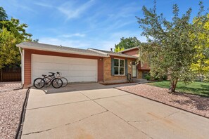 A residential house with a garage, a driveway, and a bicycle parked in the garage. - Pipit Place - Pet-friendly Home w/ Fenced Yard (Fort Collins)