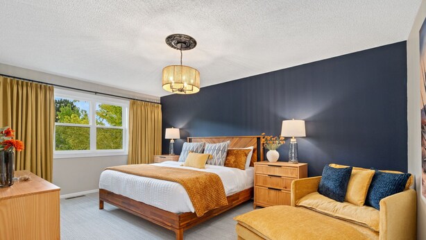 A hotel room with a bed, bedside tables, a sofa, and a window with curtains. - Pipit Place - Pet-friendly Home w/ Fenced Yard (Fort Collins)