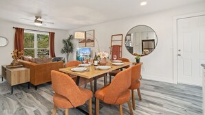 A modern living room with a sofa, a dining table set for four, and a large mirror. - Pipit Place - Pet-friendly Home w/ Fenced Yard (Fort Collins)