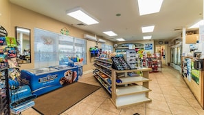 Una tienda de conveniencia con un congelador de helados Blue Bunny, estantes llenos de bocadillos y un refrigerador de Bud Light.