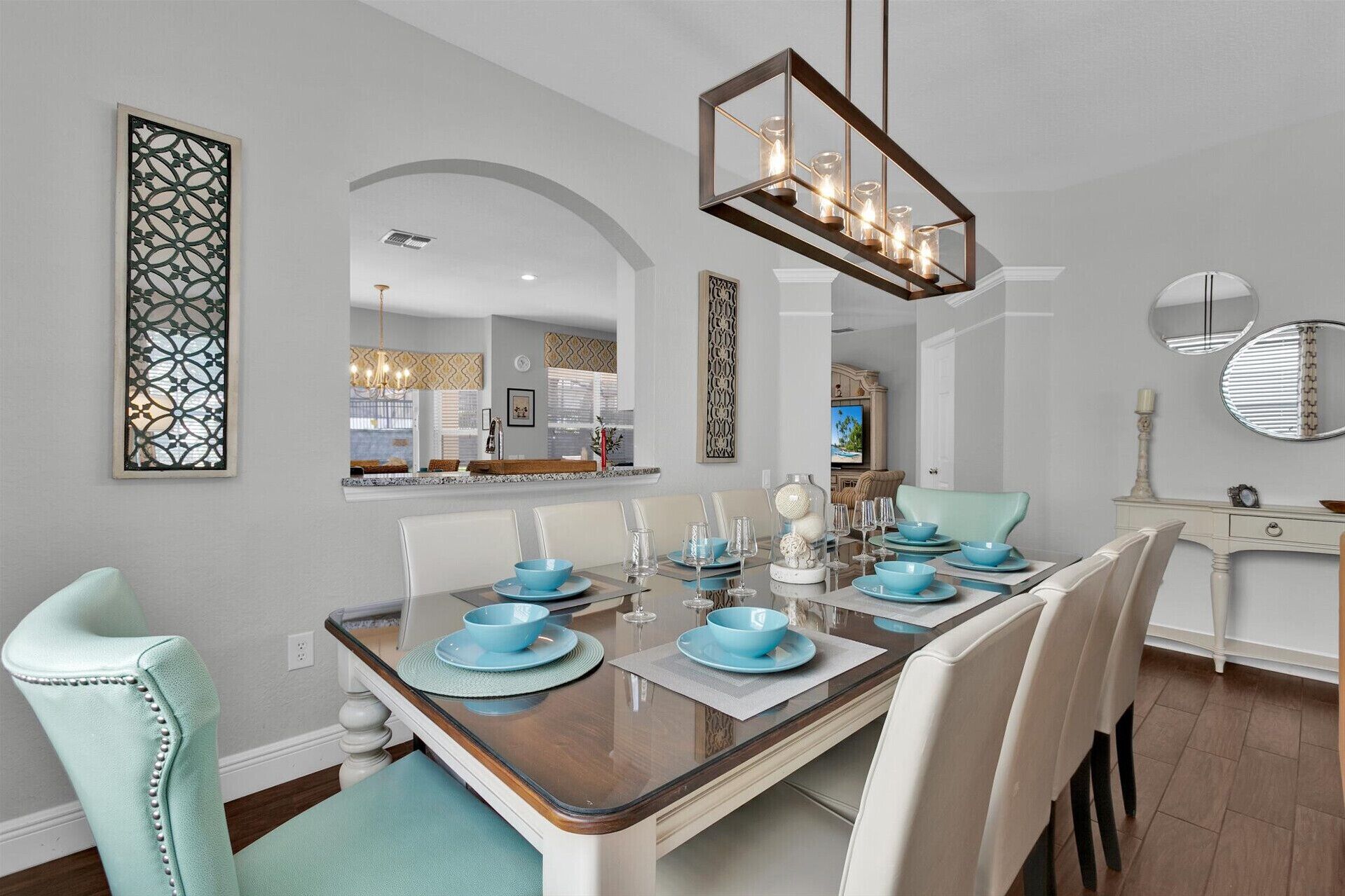 Un coin repas avec une table rectangulaire, des chaises blanches et de la vaisselle bleue.