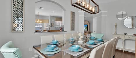 Un coin repas avec une table rectangulaire, des chaises blanches et de la vaisselle bleue.