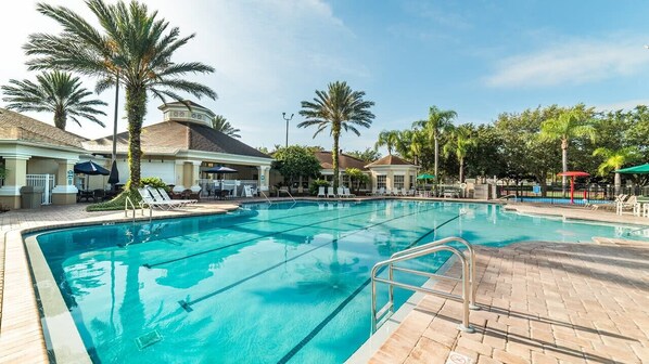 Una piscina con sillas de descanso y palmeras.