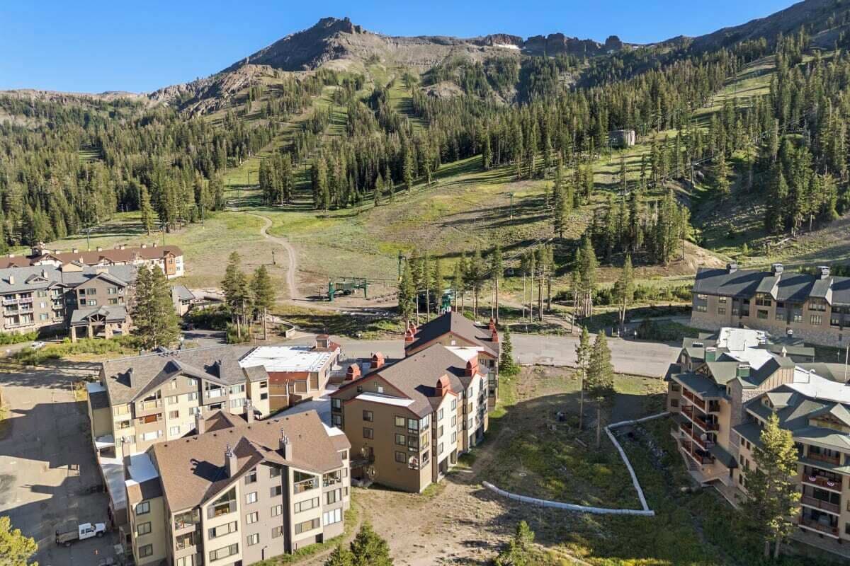 Zona residencial con edificios de varios pisos, una calle despejada y montañas al fondo.