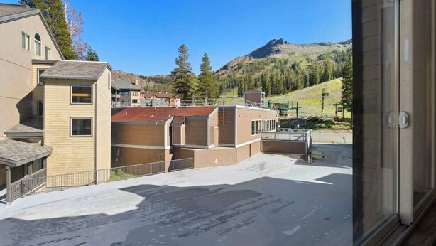 A hotel with multiple buildings, a parking area, and a mountainous backdrop. - Ski-In/Ski-Out Kirkwood Village Condo (Kirkwood)