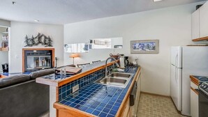 A compact kitchen with a blue tiled backsplash, a built-in oven, and a refrigerator. - Ski-In/Ski-Out Kirkwood Village Condo (Kirkwood)
