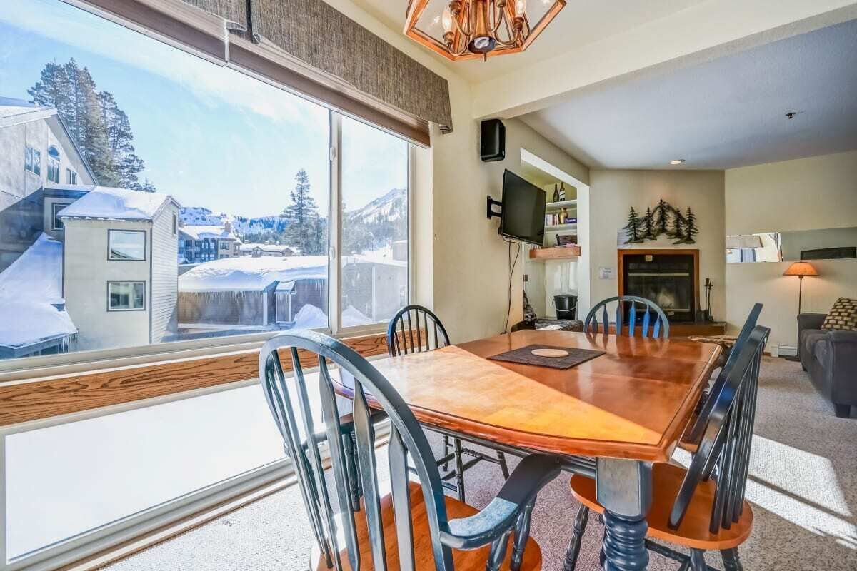 Un coin repas avec une grande fenêtre, une table en bois et des chaises.