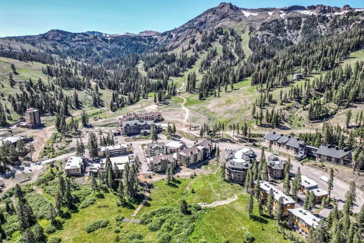 A resort with multiple buildings, surrounded by forested mountains.